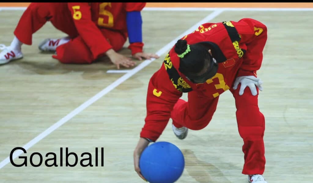 image of a goalball player at the net picking up the ball
