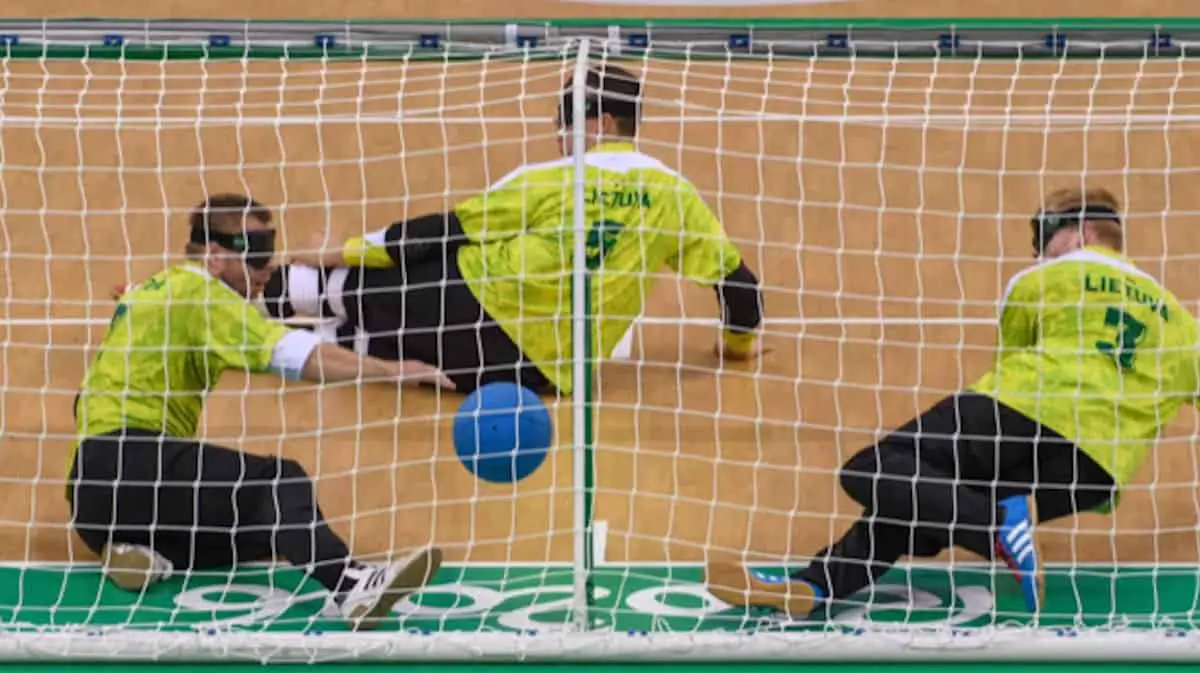 image of 3 goalball players in action defending the goal