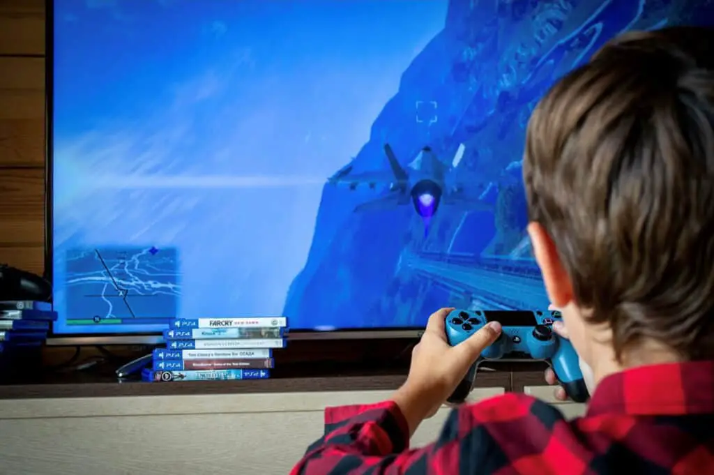 image of a boy playing a video game in front of a large screen
